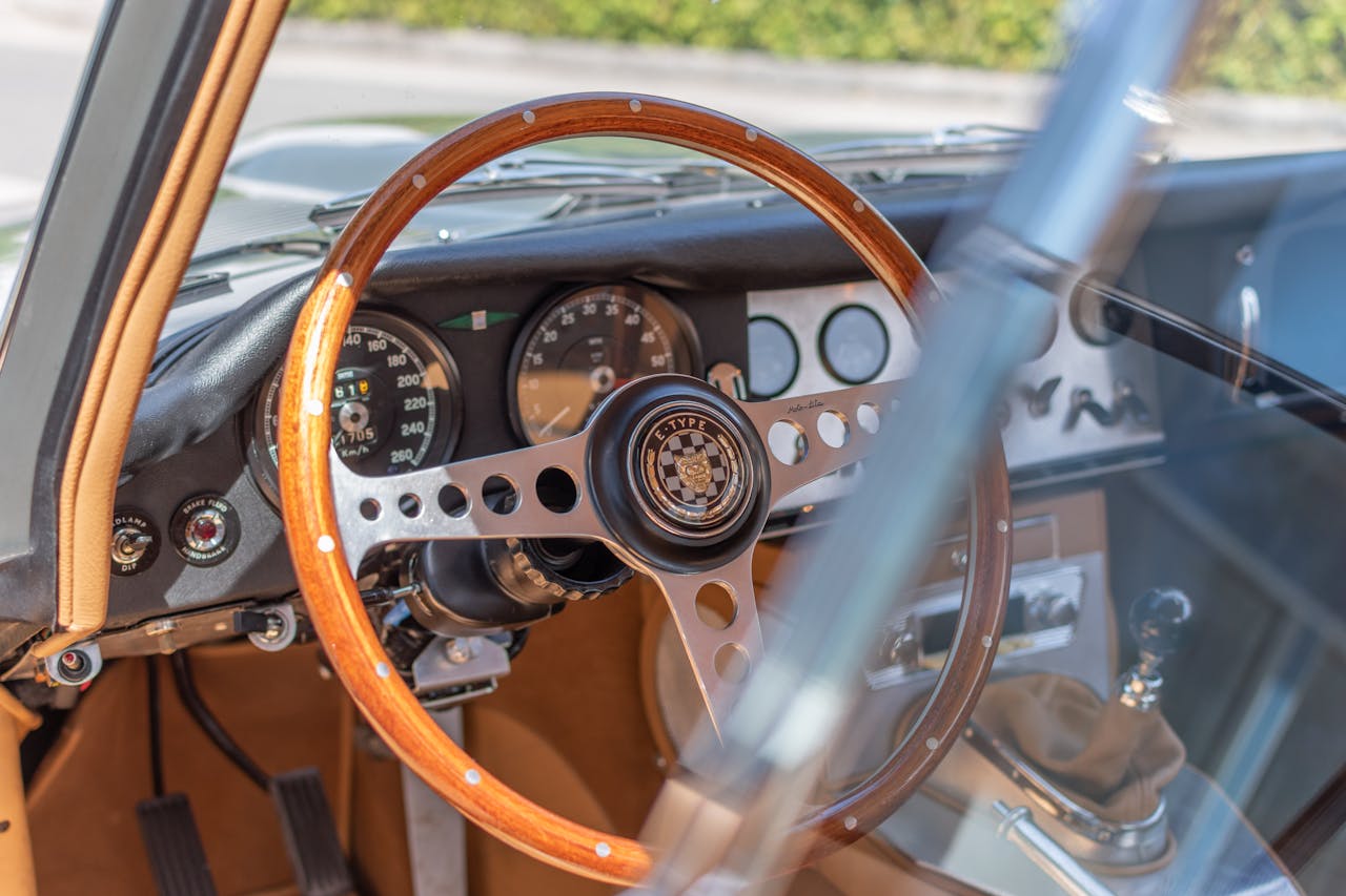 Services Close-up of a classic car interior featuring a wooden steering wheel and dashboard.