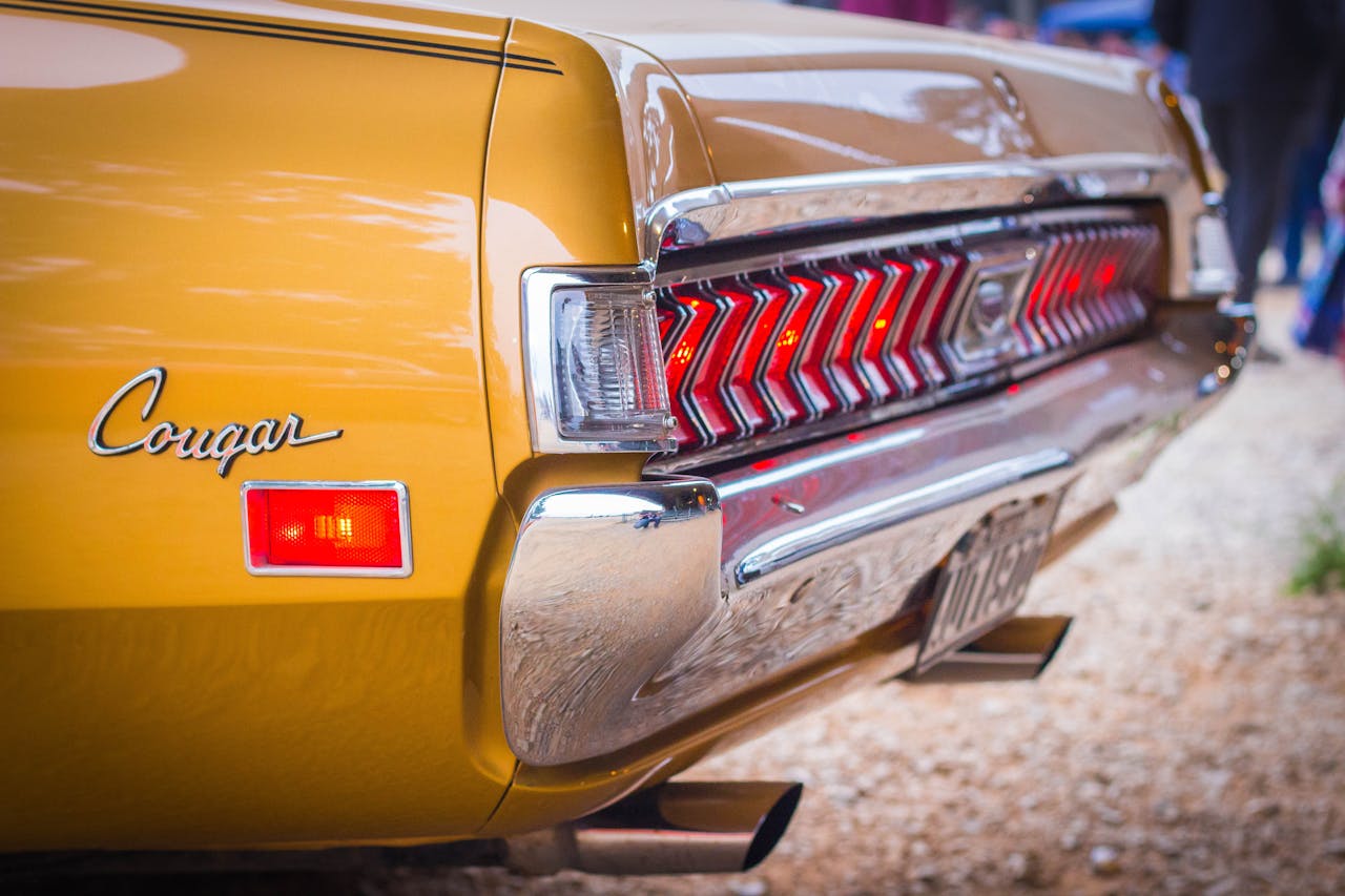 Close-up of a shiny vintage yellow Cougar car with distinctive rear design.