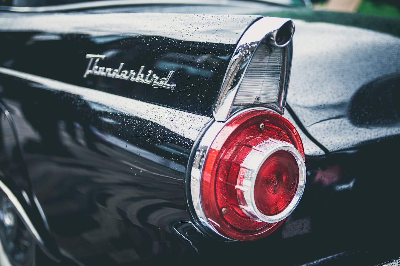 About A classic Ford Thunderbird's taillight with water droplets, reflecting vintage automotive style.